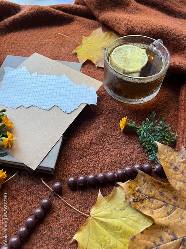 The image shows a notebook, cup of coffee, and flowers on a sweater. 