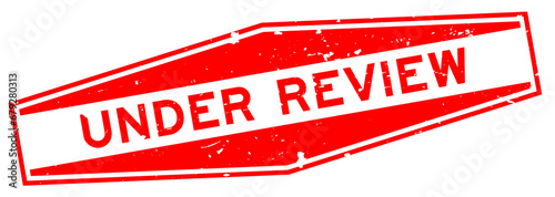 Grunge red under review word hexagon rubber seal stamp on white background