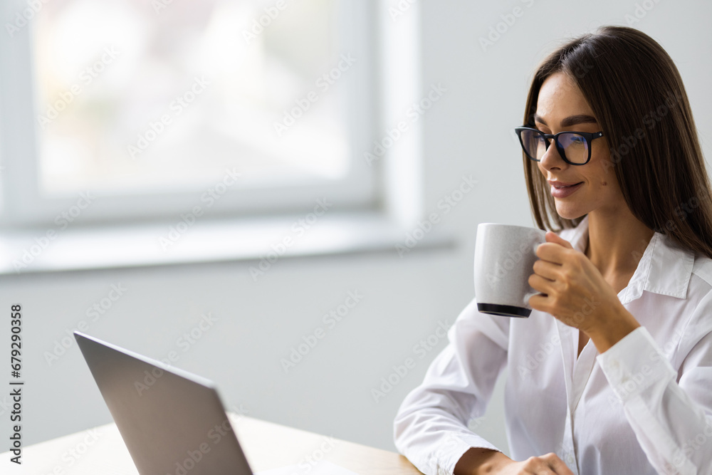 Young businesswoman with coffee cup using phone at office Young businesswoman with coffee cup using phone at office