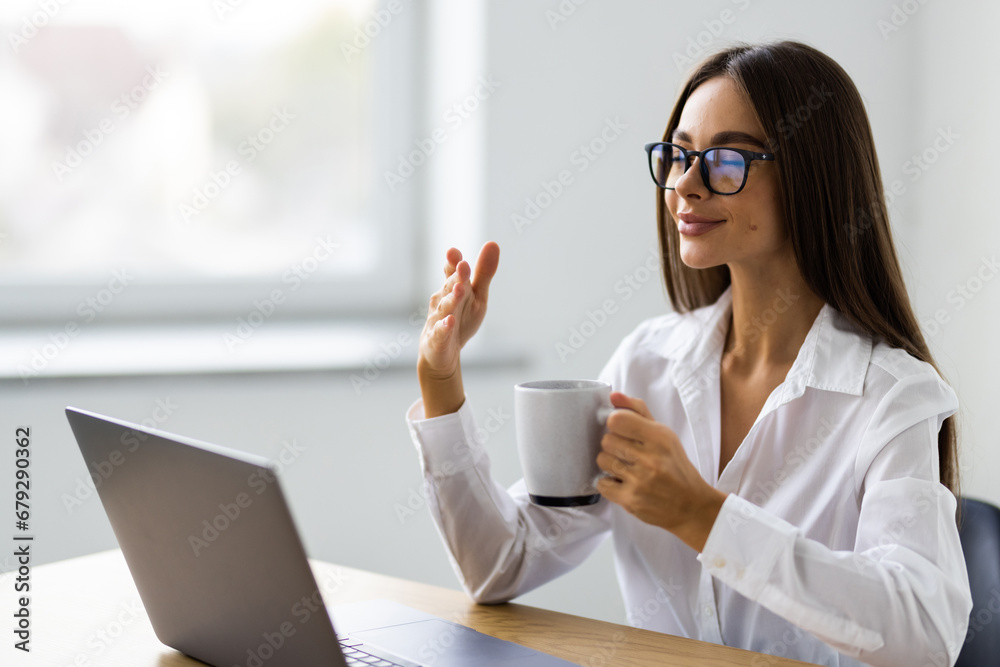 Young businesswoman sitting on the desk with with cup in office Young businesswoman sitting on the desk with with cup in office