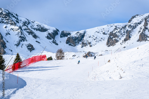 Skiers on a steep ski slope on a sunny winter day