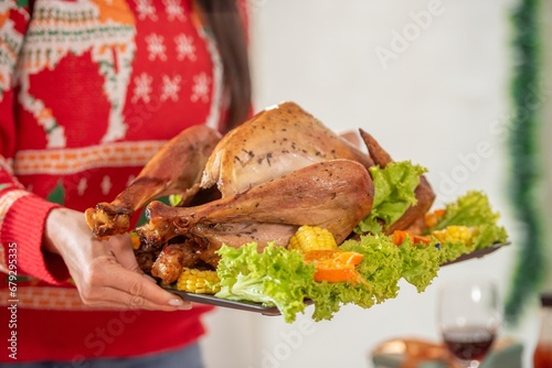 Turkey dinner Thanksgiving food. Man carry Christmas turkey food dinner Serve on table. Baked turkey chicken garnished with family Christmas tree and burning candles . Roasted turkey table setting