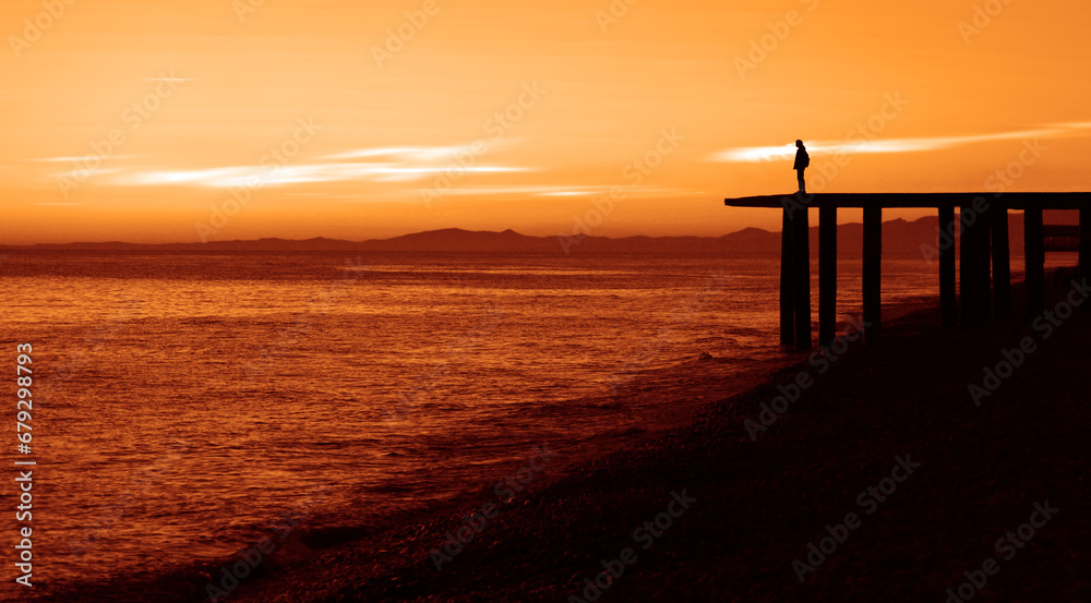 Silhouette of one alone Woman on Lakeside with majestic Sunset Cloudscape. Black sea. man wearing jacket of the sunset stands on the ocean in the water. after sun down.