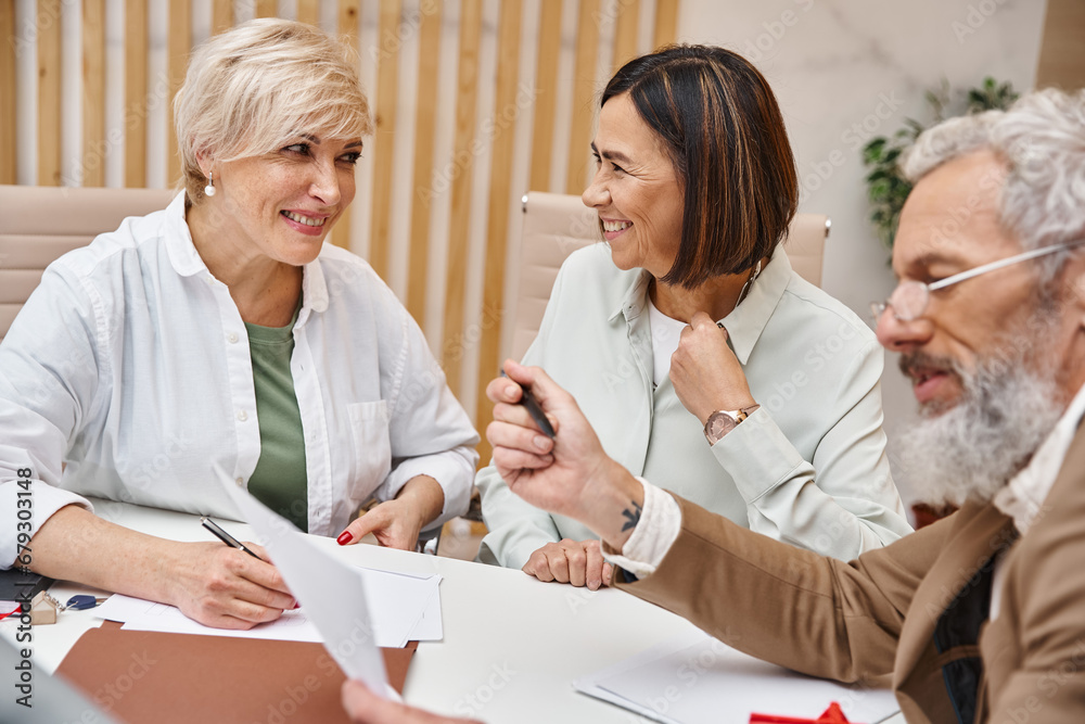happy lesbian couple discussing purchase of real estate property near bearded middle aged realtor happy lesbian couple discussing purchase of real estate property near bearded middle aged realtor