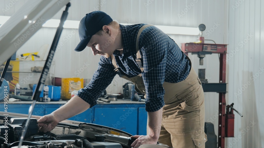 A car mechanic repairs a car. The mechanic is looking for a malfunction in the car. Engine diagnostics A car mechanic repairs a car. The mechanic is looking for a malfunction in the car. Engine diagnostics
