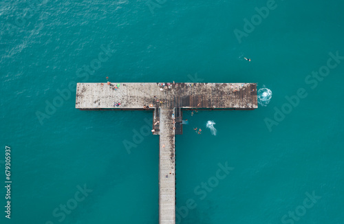 Drone aerial view of people diving in the sea from a jetty. Healthy lifestyle. People swimming in the ocean. Limni Pier Paphos