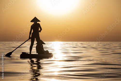 a woman with a child on a sup board in the sea swim against the background of a beautiful sunset, Standup paddleboarding photo