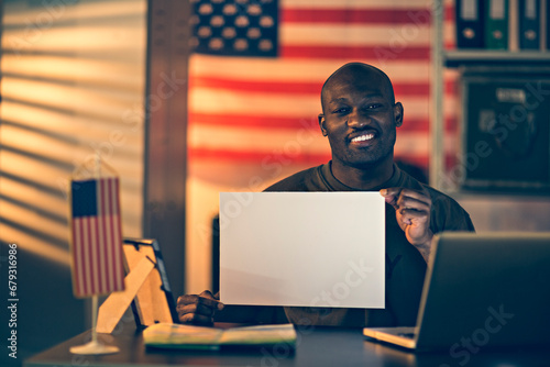 Cheerful Army Man Holding Blank Sign in Office with American Flag Background photo
