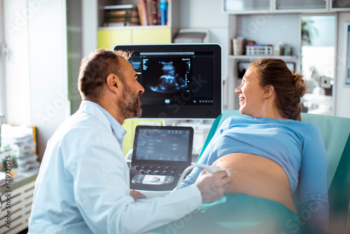 Obstetrician Moving Transducer on the Belly of the Future Mother At Hospital photo