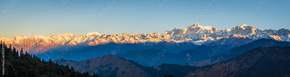 Panoramic view during sunset over snow cladded gangotri group mountain peaks falls in Greater Himalayas mountain range from Chopta, Uttarakhand, India.