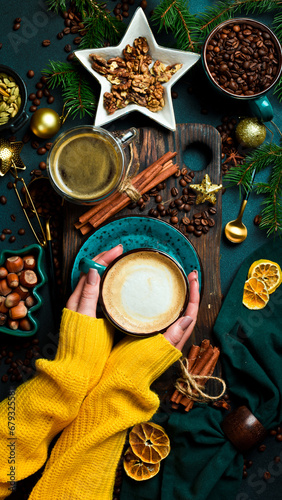 Christmas concept. Cup of fragrant cappuccino coffee in female hands. New Year's decor. On a dark background.