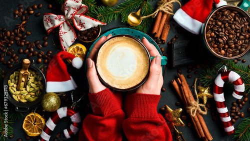 Cappuccino, hot chocolate latte coffee with Merry christmas drawing on warm wooden background, Christmas winter cozy cup with hot chocolate drink in woman hands, top view copy space