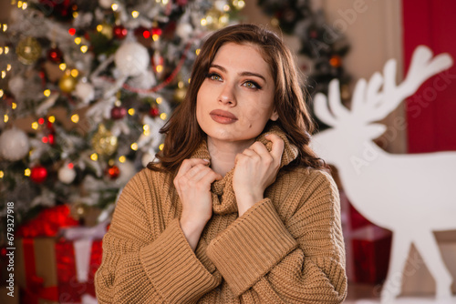 Beautiful young woman with a gift in her hands on the background of a Christmas tree.