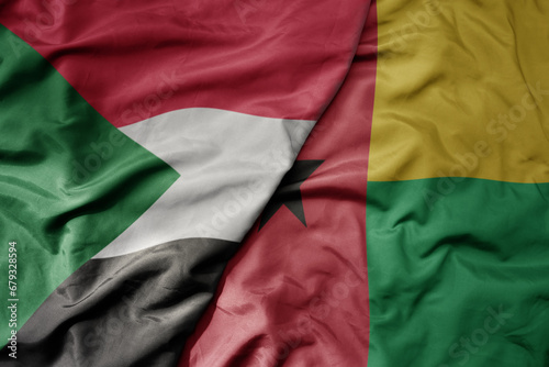 big waving national colorful flag of sudan and national flag of guinea bissau .