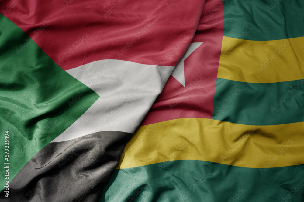 big waving national colorful flag of sudan and national flag of togo .