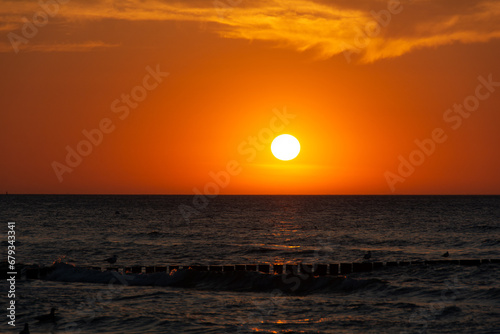 Fototapeta Naklejka Na Ścianę i Meble -  Sunset over the sea with breakwaters and birds