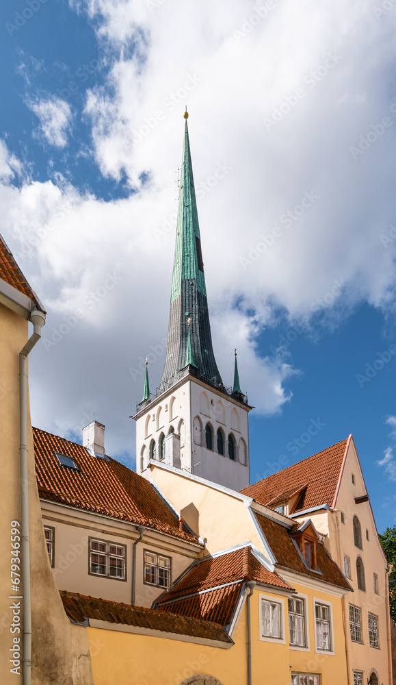 Obraz premium Tower of St Olaf's Church behind traditional buildings in old town of Tallinn, Estonia.