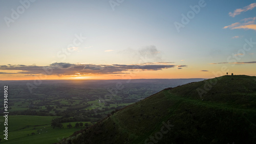 The sun rises over the Skirrid Fawr mountain near Abergavenny in the Brecon Beacons Black Mountains national park. morning walkers enjoy rugged natural beauty in Bannau Brycheiniog South Wales