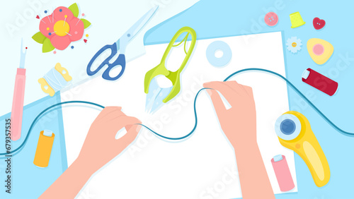 Female hands with thread on the background of a table with sewing tools
