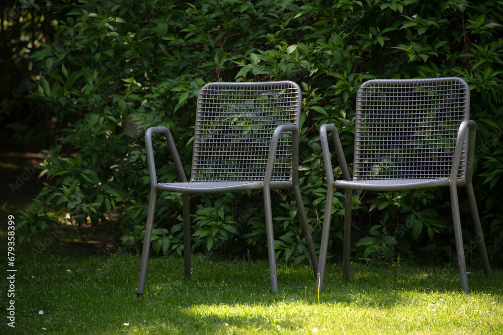 Metal chairs in spring garden. Metal garden furniture for picnics and birdwatching Metal chairs in spring garden. Metal garden furniture for picnics and birdwatching