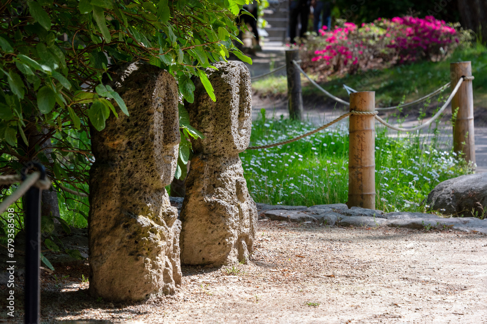 Fototapeta premium Korean traditional stone statues in the garden. Man and woman family garden decoration, old stone totems. Korean style garden park