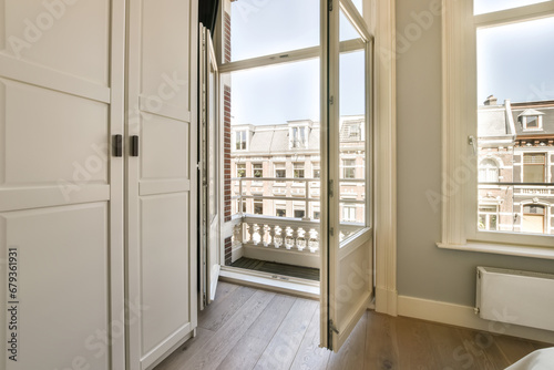 a room with wooden floors and white walls, there is an open door that leads out to the balcony area
