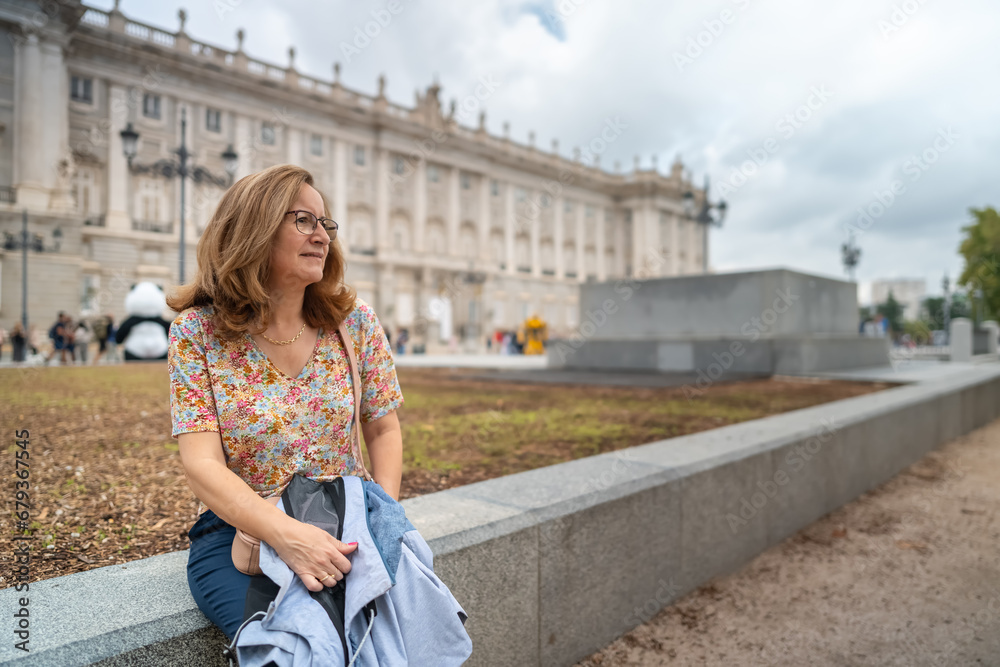 Tourist woman resting in front of the Royal Palace of Madrid in Spain.