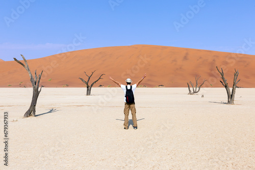 A young tourist with open arms at Deadvlei, Sossusvlei. Namibia, Africa