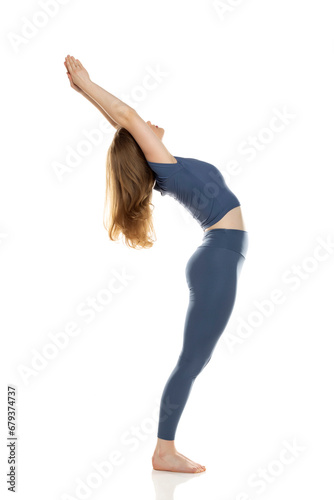 Full body, side view young woman in sportswear practicing yoga on white background