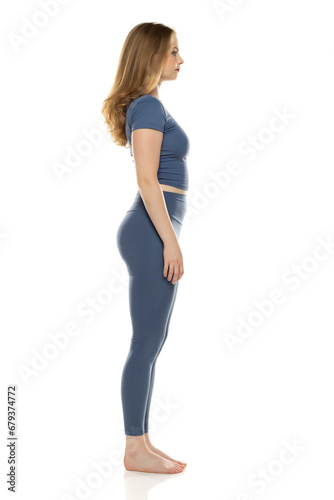 Full body, side view young woman in sportswear posing on white background © vladimirfloyd