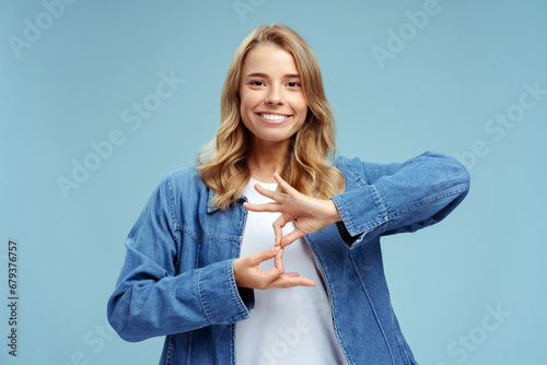 Smiling confident sign language interpreter or teacher communicating by hands gestures isolated on blue background. Nonverbal communication concept