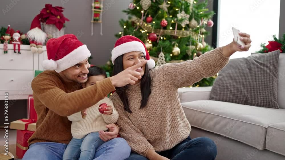 Couple and son make selfie by smartphone sitting on floor by christmas tree at home Couple and son make selfie by smartphone sitting on floor by christmas tree at home