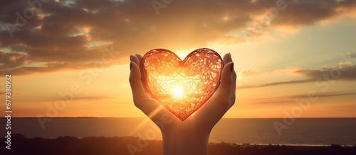 Hands holding heart shape on beach sunset background