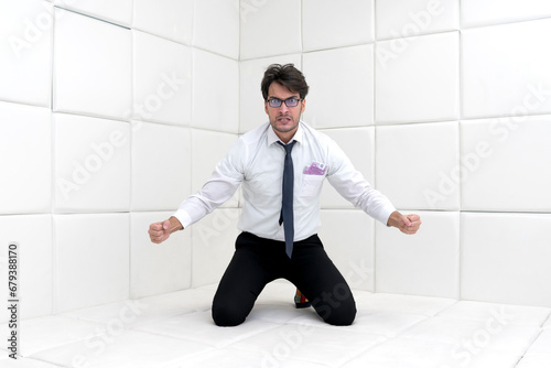 Sad and frustrated businessman in formal wear sitting in a white room in a mental hospital © Vitaliy