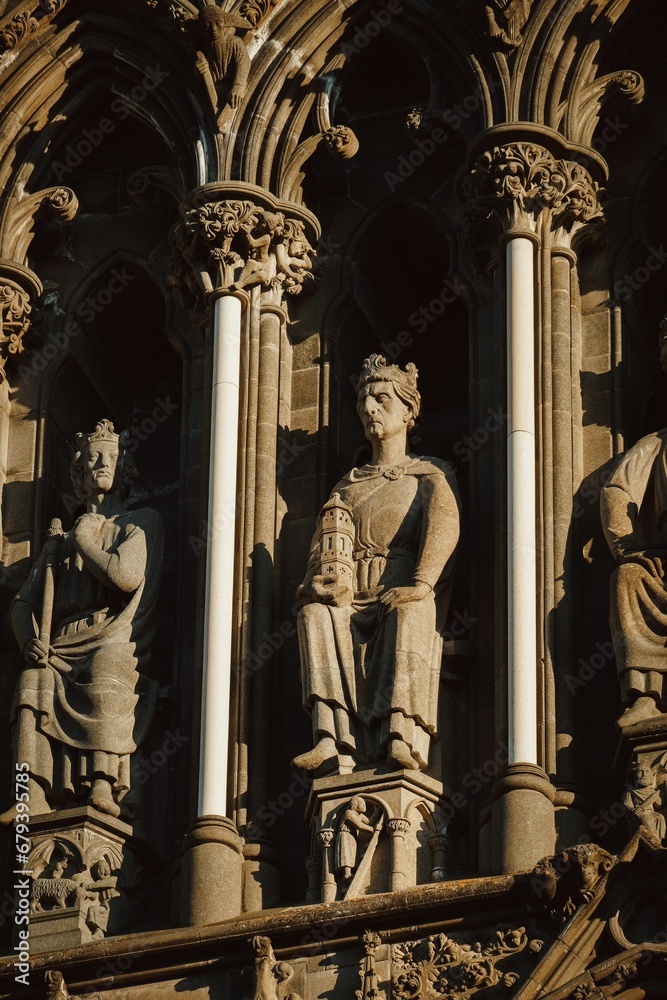 several sculptures on the outside of a large building with carved columns and a statue of