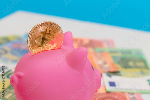 Pink Piggy Bank with Bitcoin Coin on the Euro Banknotes. Small Money Box for Cash or Coins. Money Saving Concept