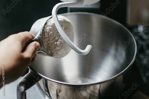 the hand of a woman mixing an item in a silver bowl