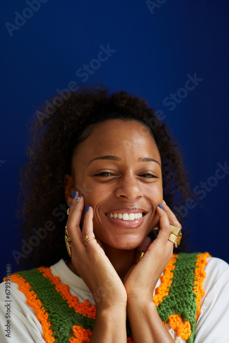 Portrait of a biracial woman with curly natural hair posing and smiling with manicure and stylish rings. Concept of diverse, stylish, fashion and beauty and jewelry