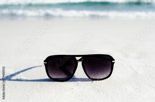 a pair of sunglasses resting in the sand at the beach