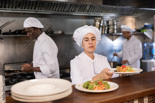 Female chef puts ready meals on shelves in restaurant