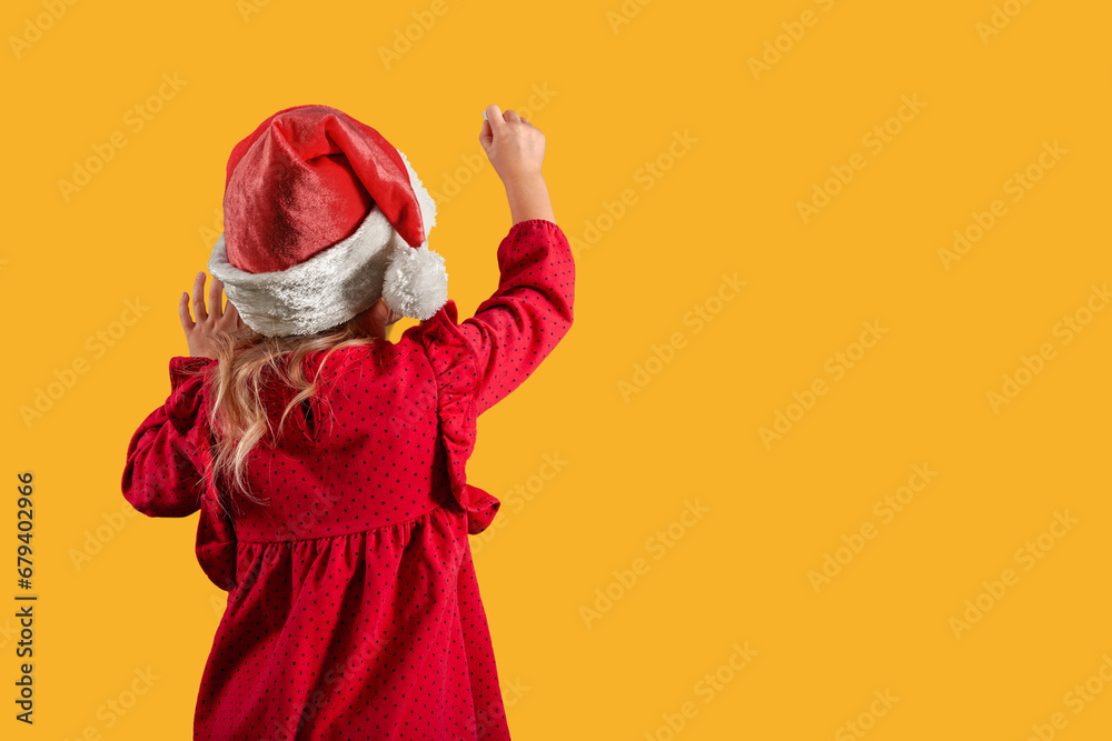a Girl in santa claus hat draws christmas drawing on the blackboard