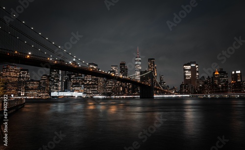 brooklyn bridge across the east side of manhattan at night with lights shining down