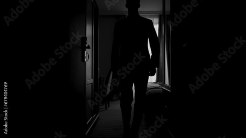 a dark black corridor and a room along which a man in a jacket and a classic suit walks, a businessman and a gentleman go to a business meeting in the office photo