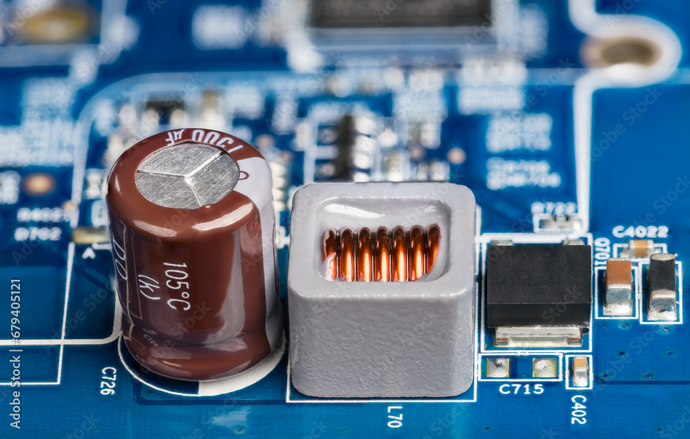 Closeup of inductor, electrolytic capacitor or transistor on blurry PCB