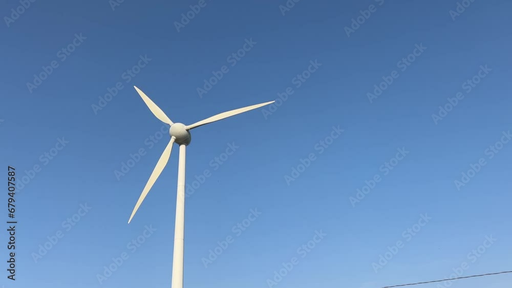 Wind turbine working against blue sky in bright sunlight Wind turbine working against blue sky in bright sunlight