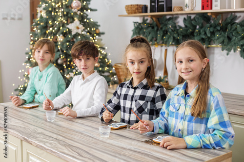 Group children draws food paints on Christmas homemade gingerbread cookies. Christmas concept. © Olha Tsiplyar