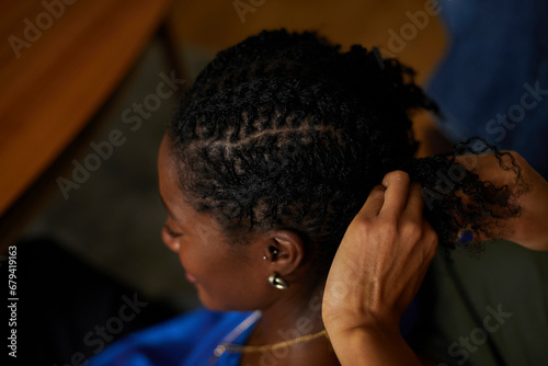 Close up of a black woman having her natural hair braided. Concept of diverse, stylish, fashion, natural hair and beauty and jewelry 