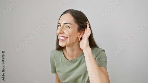 Vibrant young hispanic woman in casual clothes strikes a gossip-listening gesture. exudes charm despite her deafness. isolated white background capturing every glint of secret rumors. photo