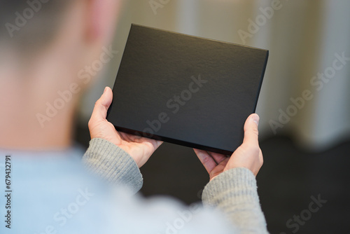 top view of an black voucher gift box as mockup for black friday offers holding with hands of a man photo