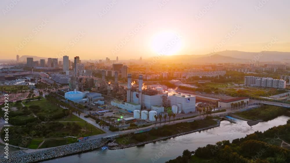 Aerial drone view of Barcelona at sunset, Spain. Power plant and residential buildings, greenery, water channel Aerial drone view of Barcelona at sunset, Spain. Power plant and residential buildings, greenery, water channel